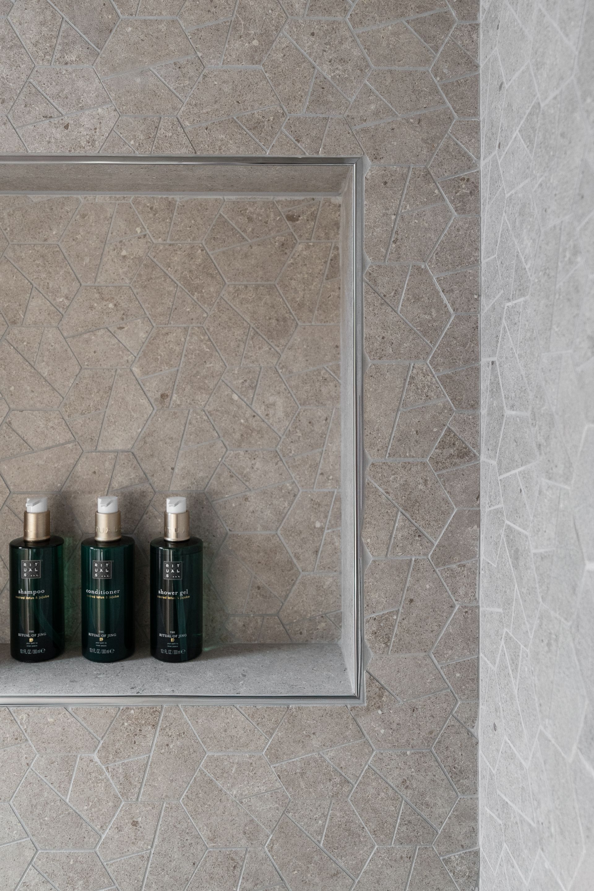 Chalet Escapade Three bottles of shampoo and conditioner are sitting on a shelf in a shower.