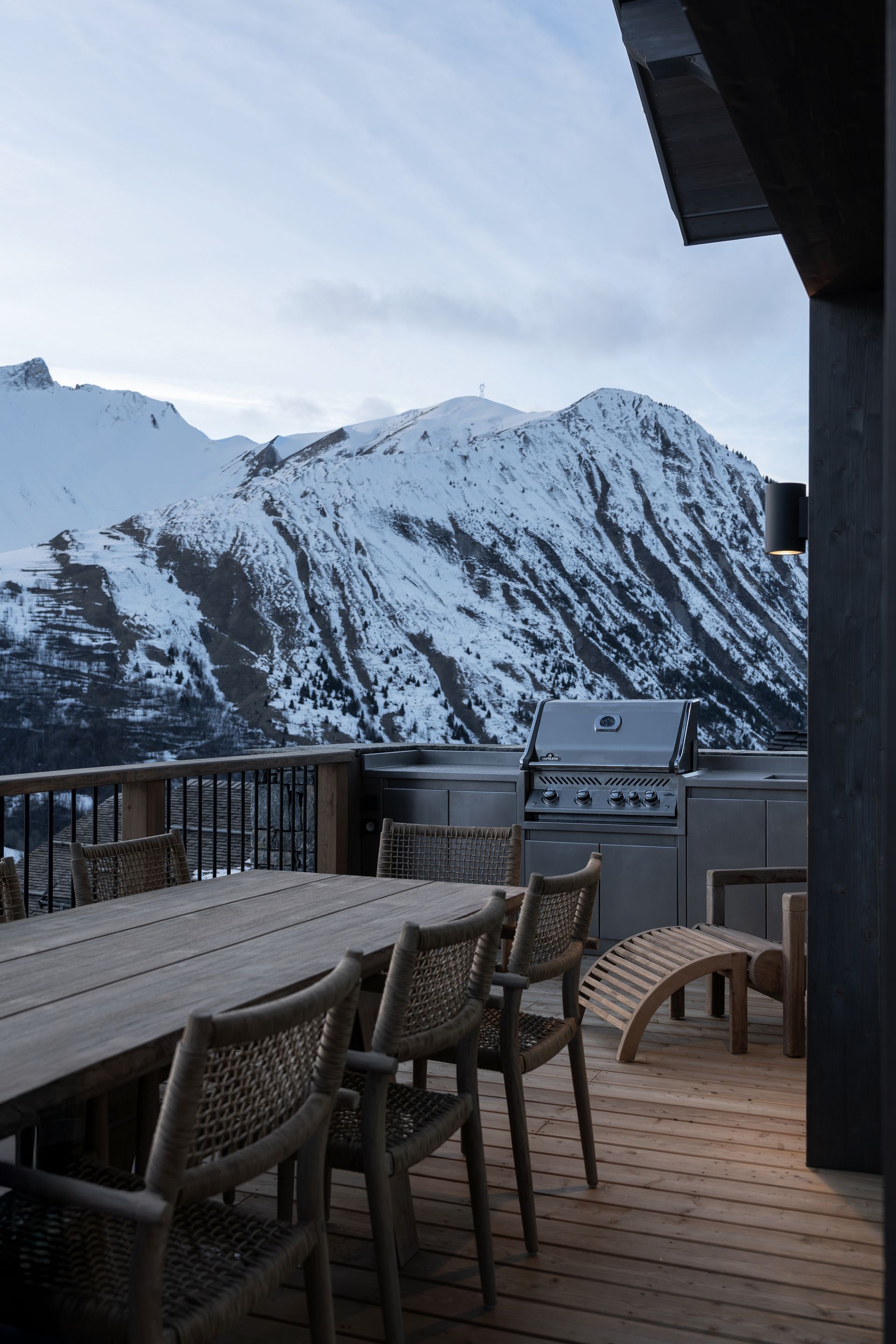 Chalet Escapade There is a table and chairs on the deck with a mountain in the background.