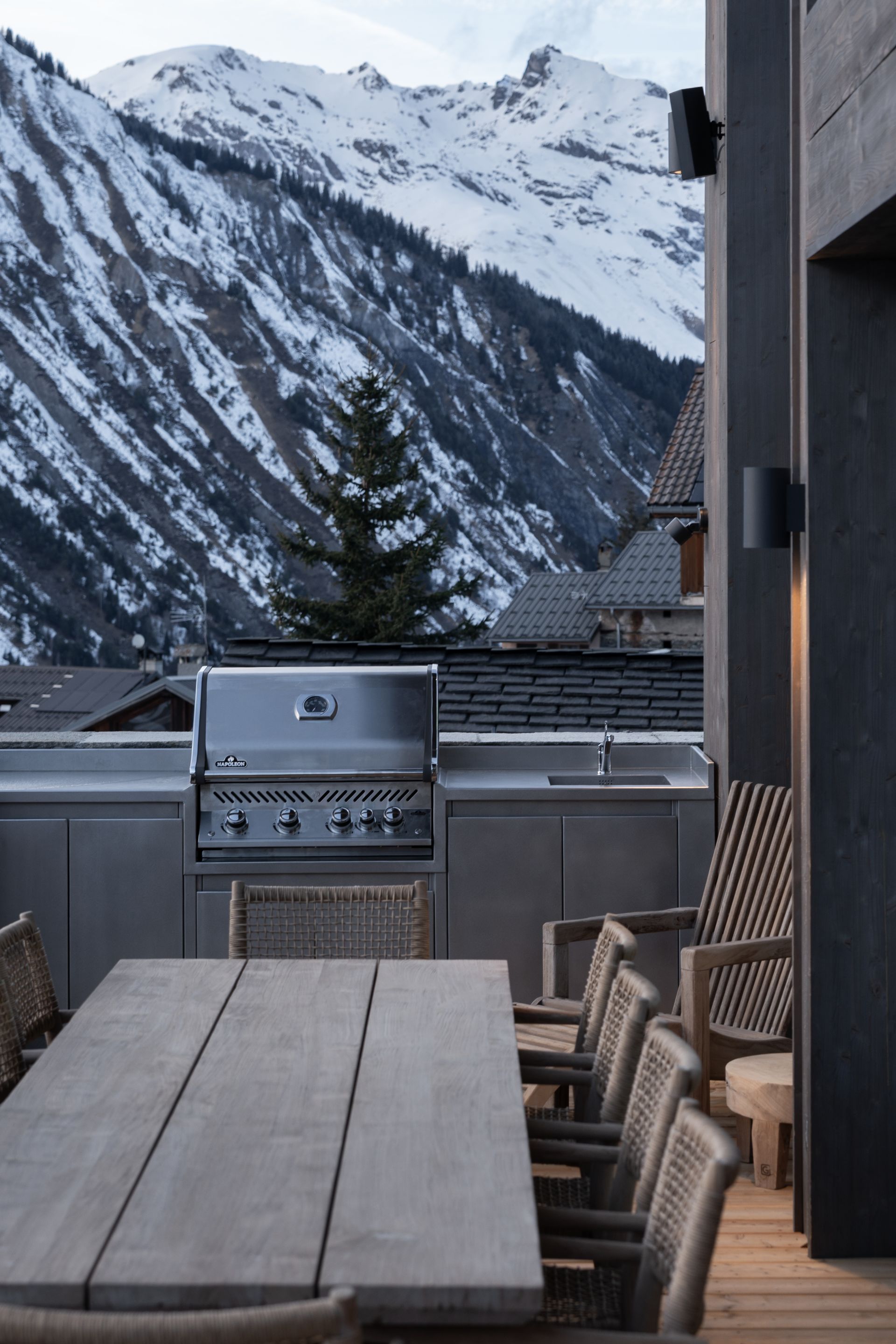 Chalet Escapade A table with chairs and a grill with mountains in the background