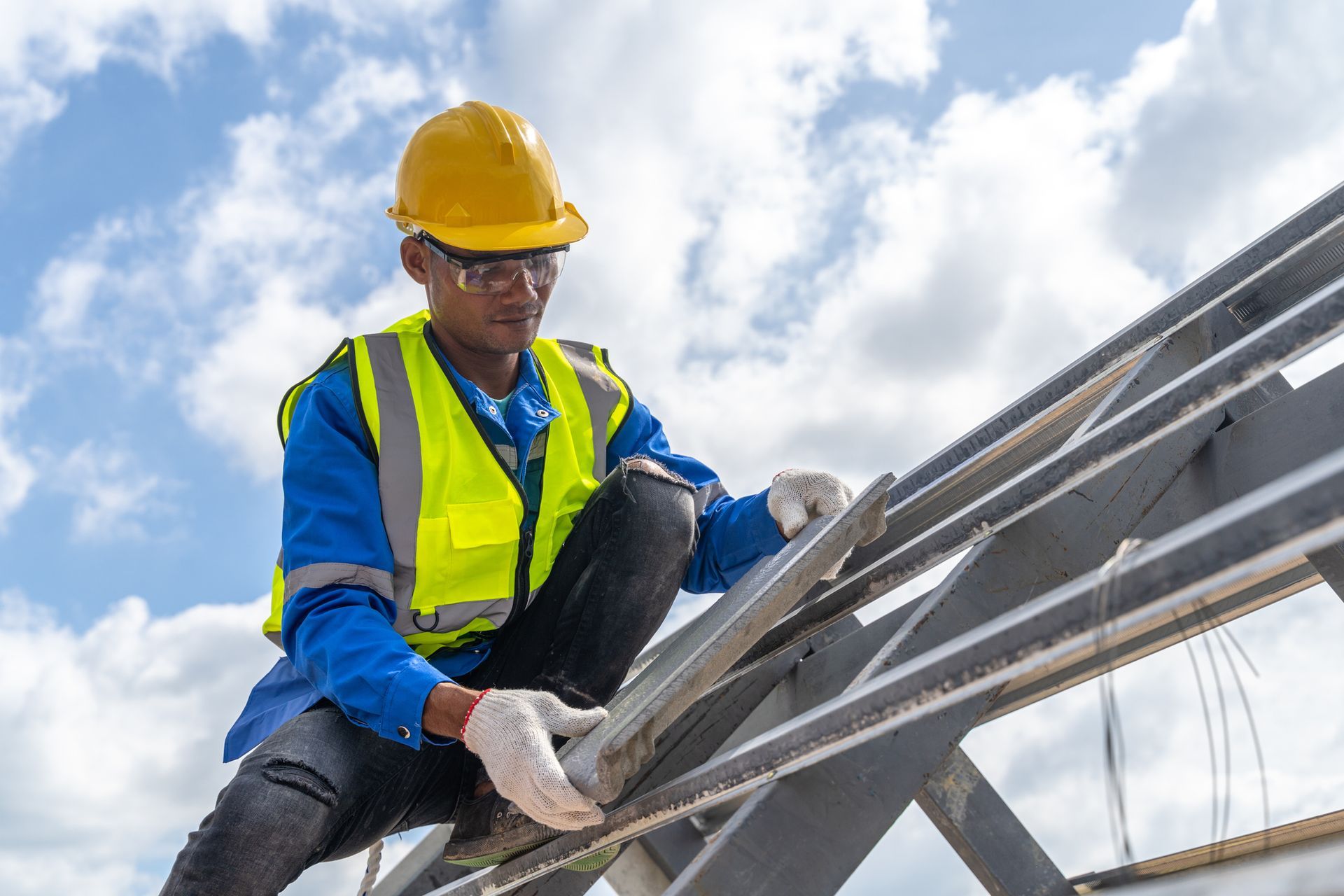 Roofing contractor wearing construction gear installs a new roof tile in a residential construction.