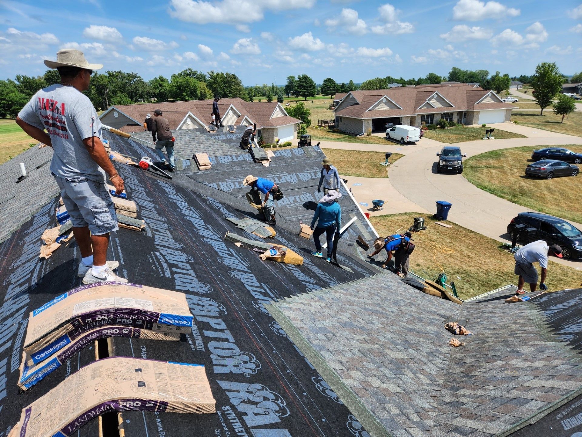 Roofing crew working on a house roof on a sunny day.