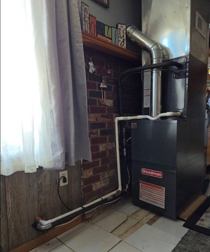 Basement utility area with a black furnace, silver ducts, and a small window with curtains.