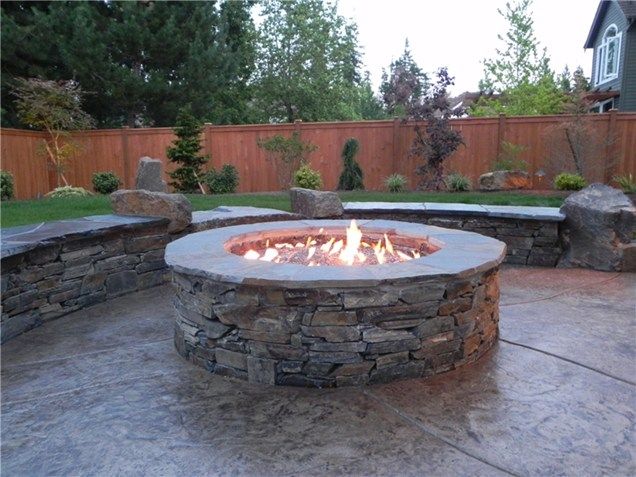 A fire pit in a backyard with a wooden fence in the background