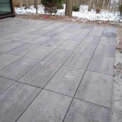 A patio with a lot of tiles on it and trees in the background.