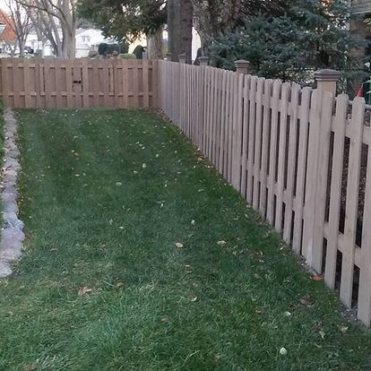 A wooden picket fence surrounds a lush green yard.
