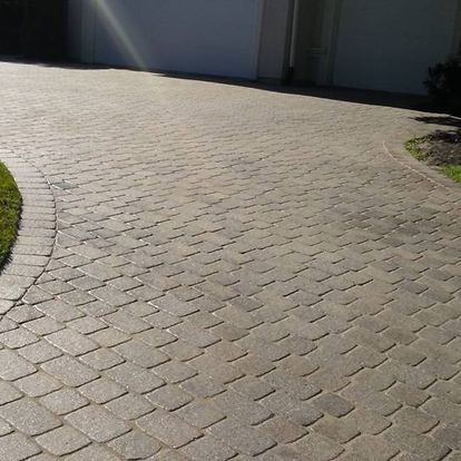 A brick driveway leading to a garage and a house.