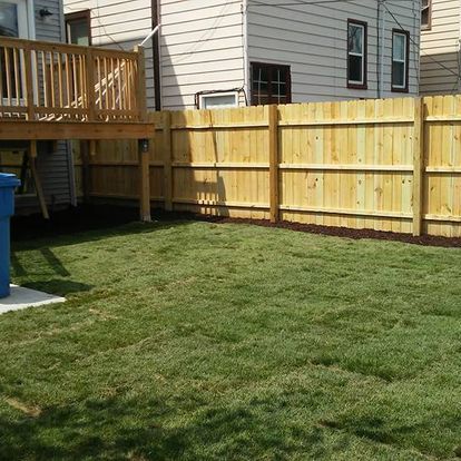 A backyard with a wooden fence and a deck