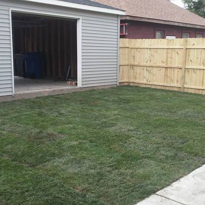 A backyard with a wooden fence and a garage.
