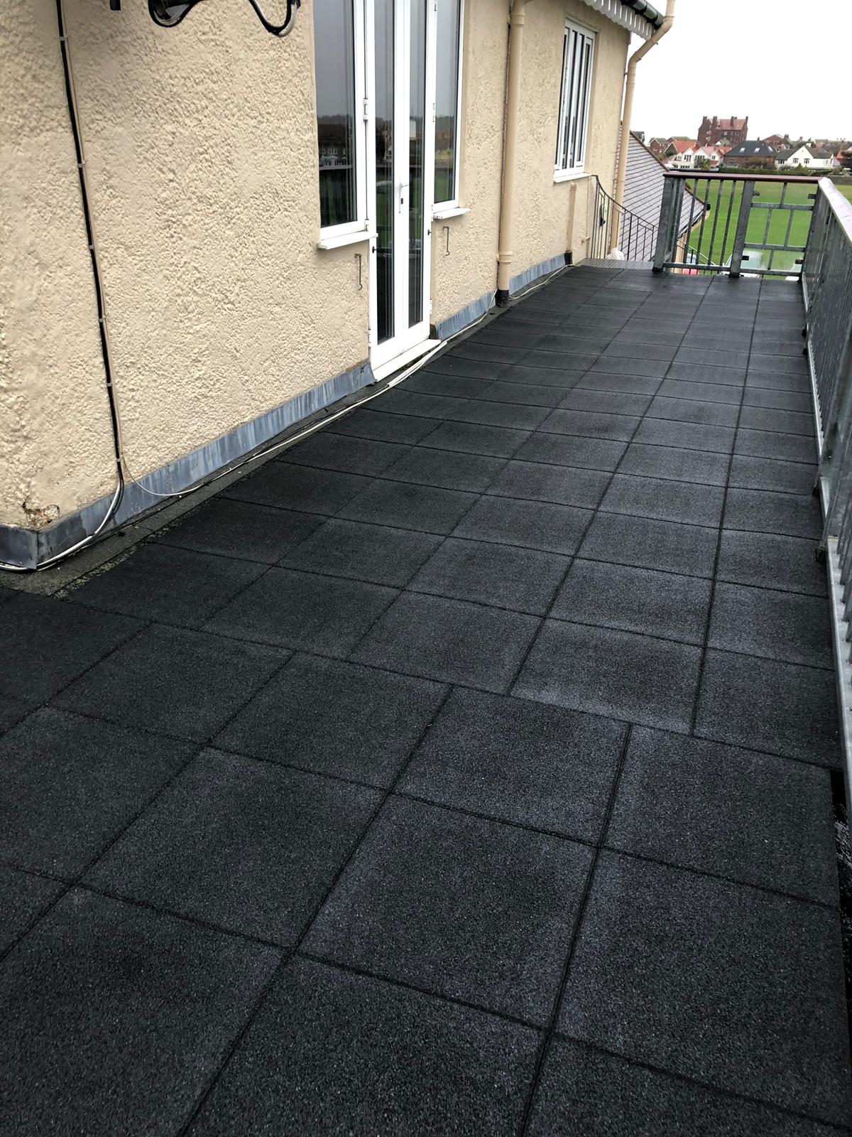 a balcony with black tiles and a white door