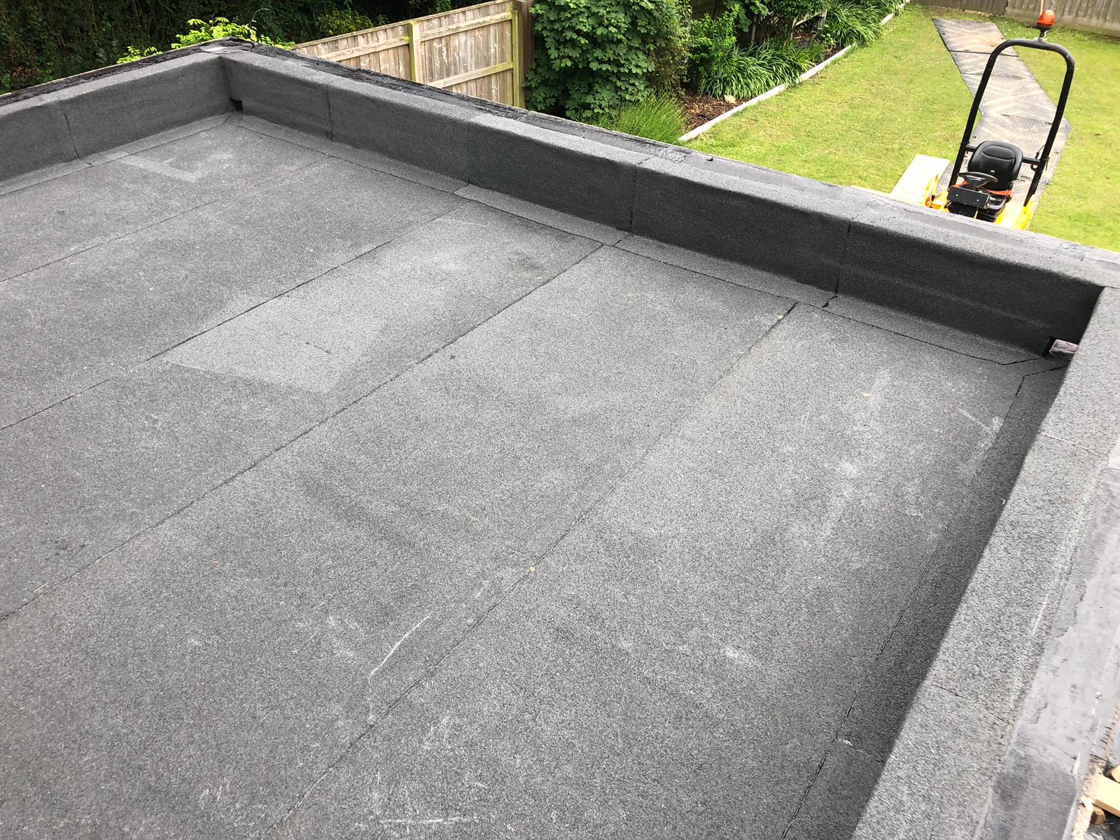 a black roof with a lawn mower in the background