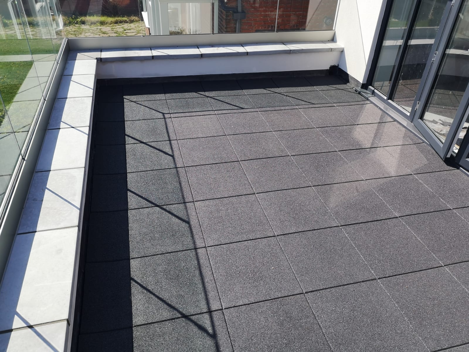 a balcony with black tiles and a glass railing