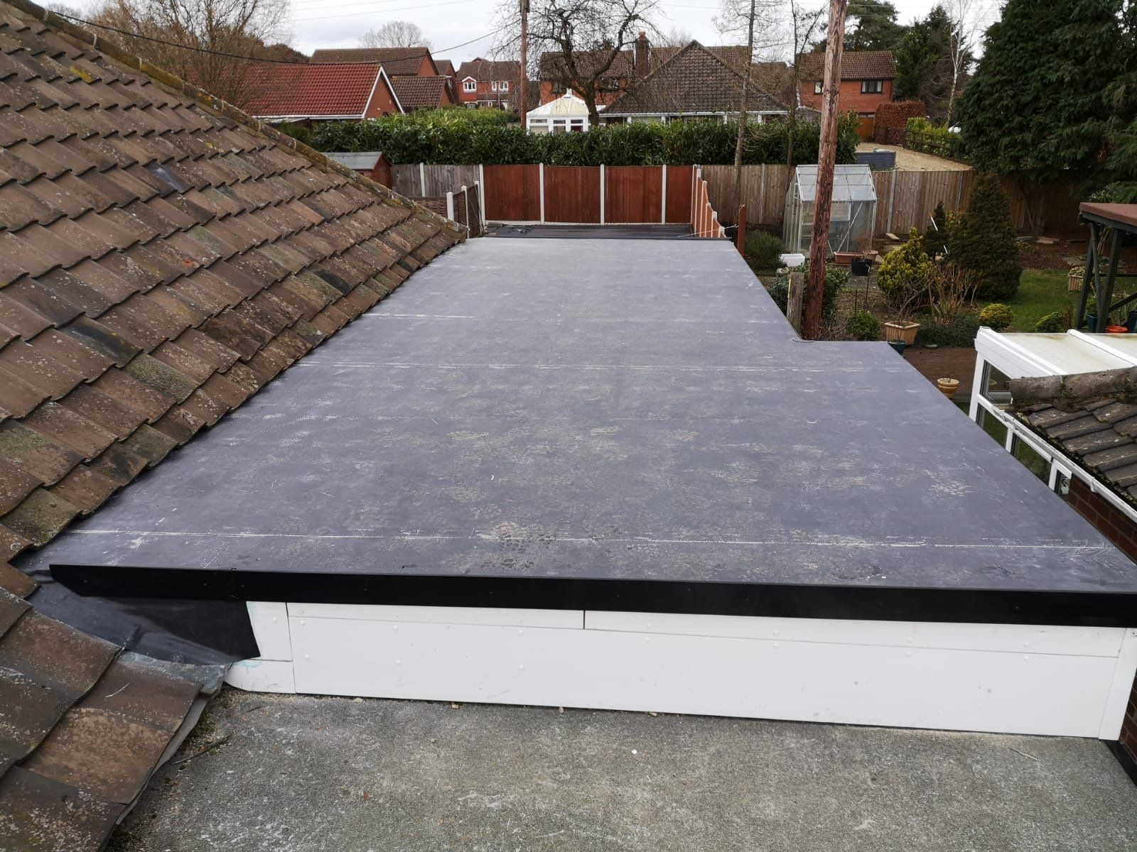 a roof with a black roof and a wooden fence in the background