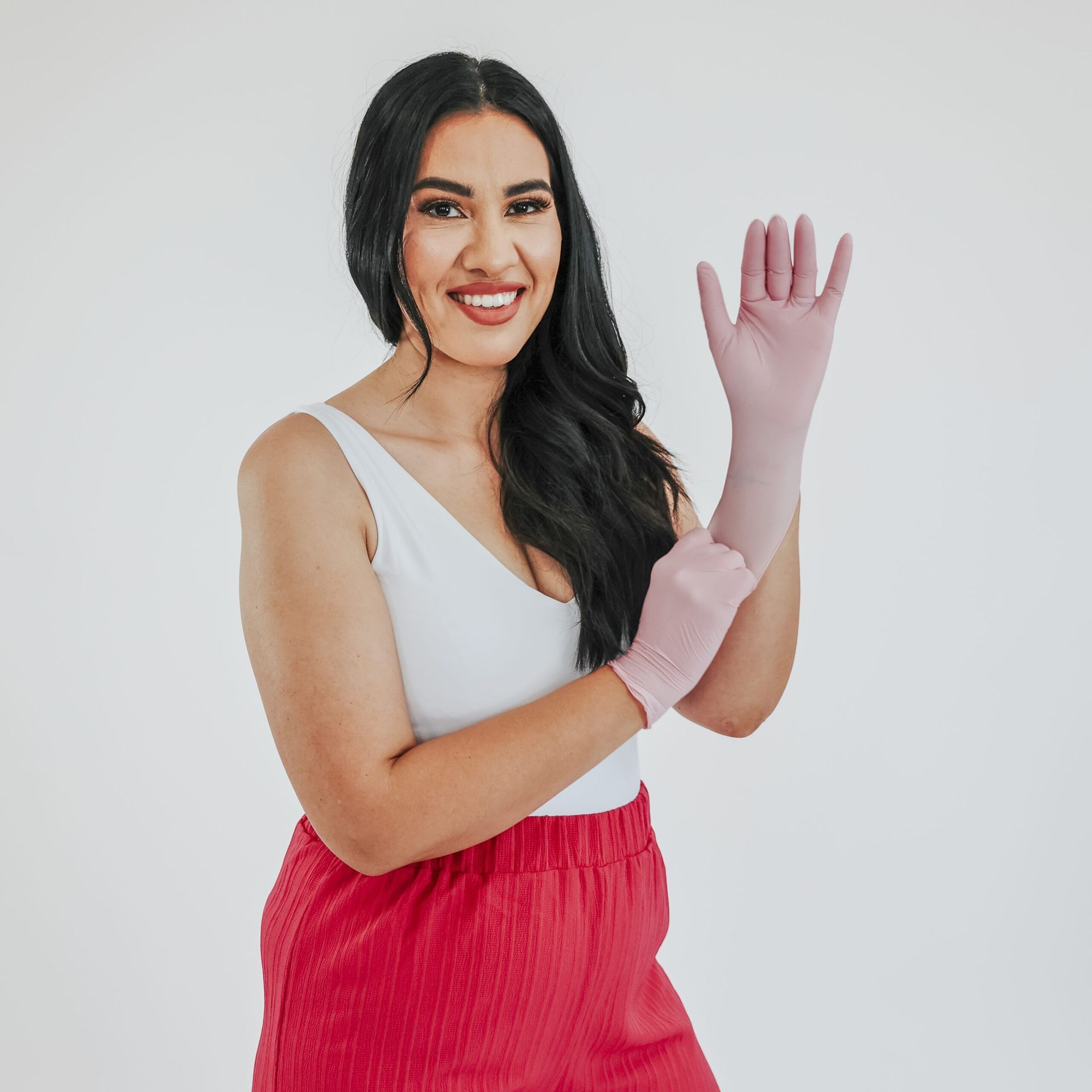 A woman wearing pink gloves and red shorts is smiling.