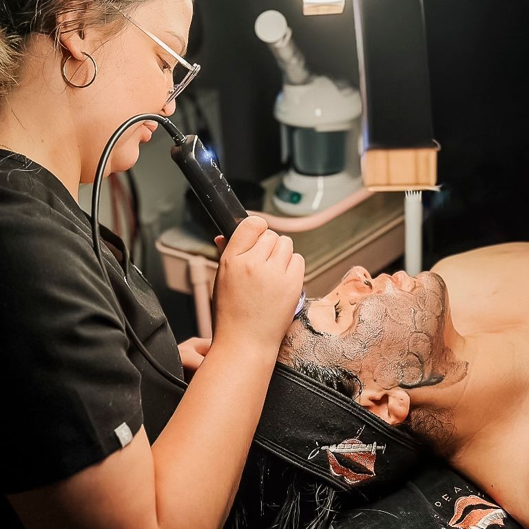 A woman is applying a mask to a man 's face