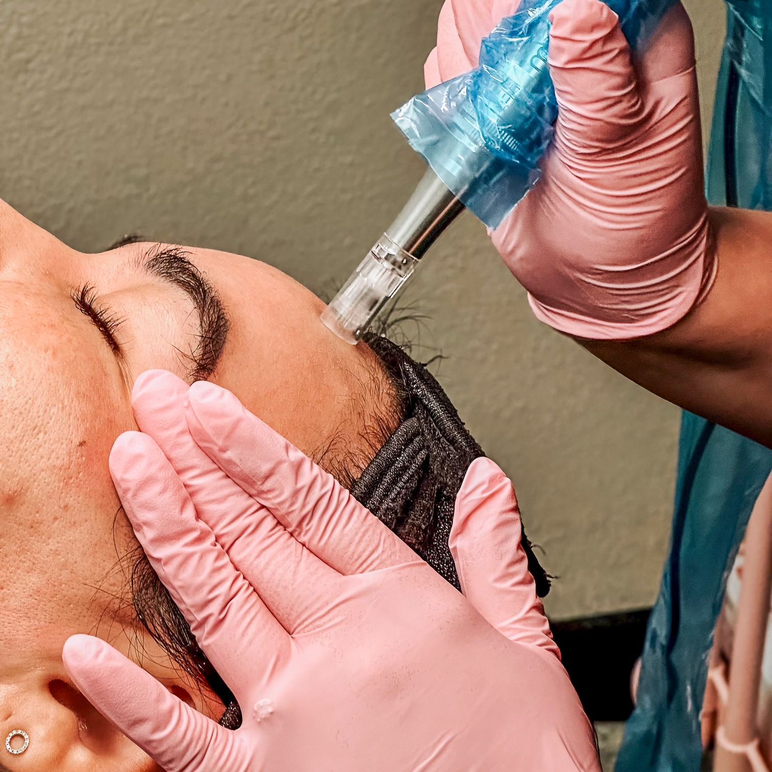 A woman wearing pink gloves is getting a treatment on her face