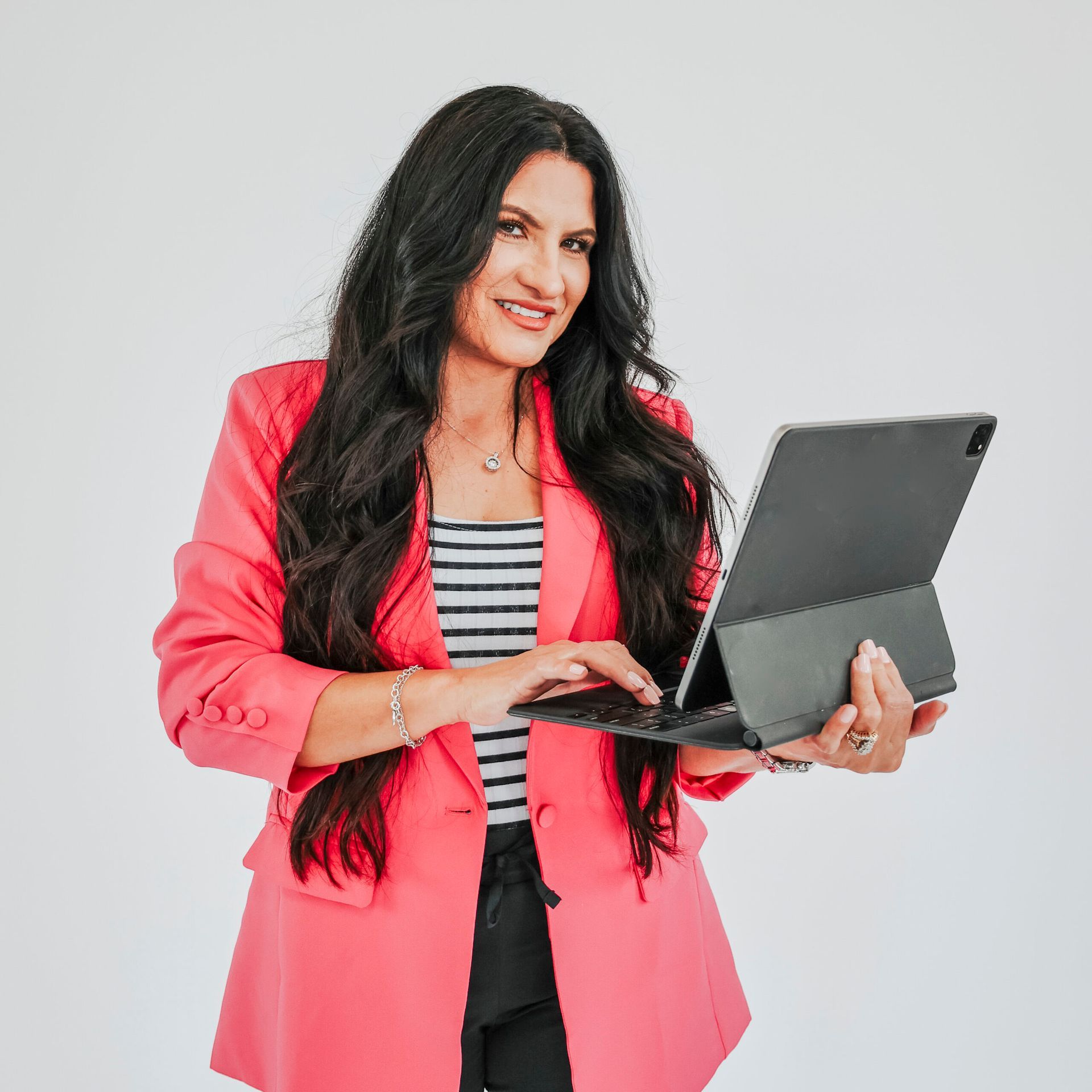A woman in a pink jacket is holding a laptop computer.