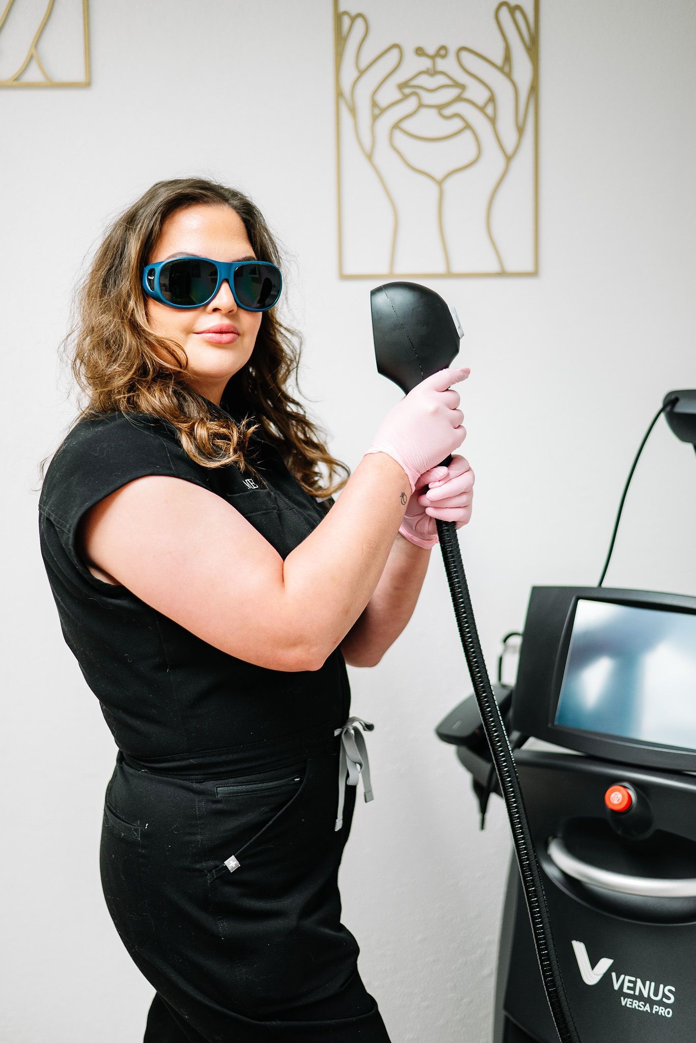 Woman in blue eye protection holding laser device in medical office.