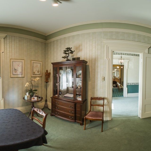 Room with antique furniture, green carpet, and light green striped wallpaper.