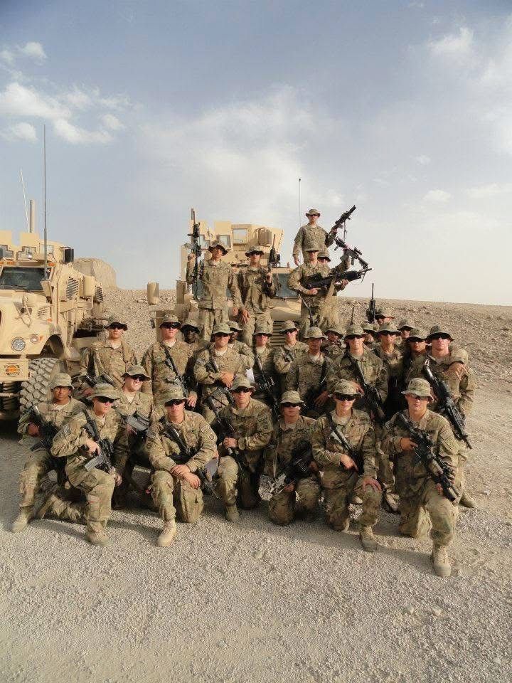 A group of soldiers are posing for a picture in front of a military vehicle.