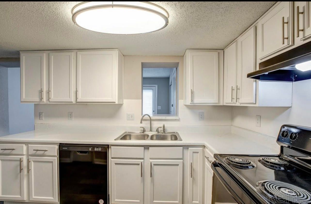 A kitchen with white cabinets and black appliances