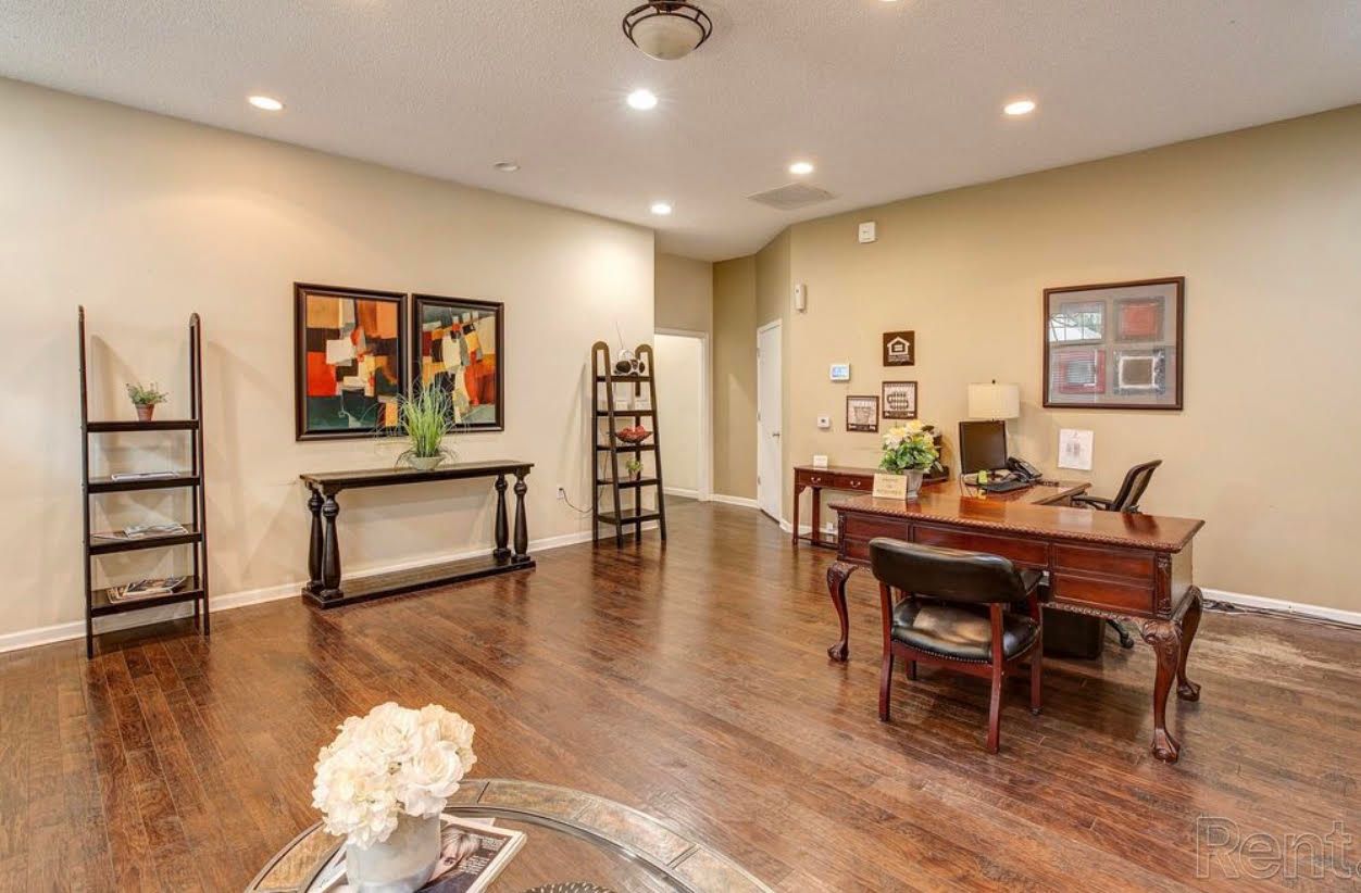 A living room with hardwood floors , a desk and chairs.