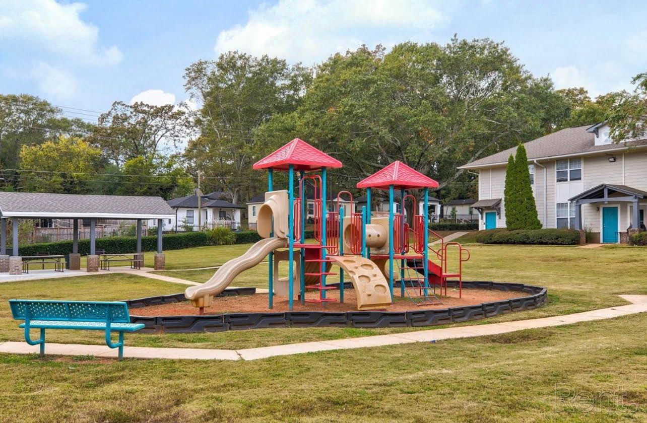 A playground with a slide and a bench in a park.