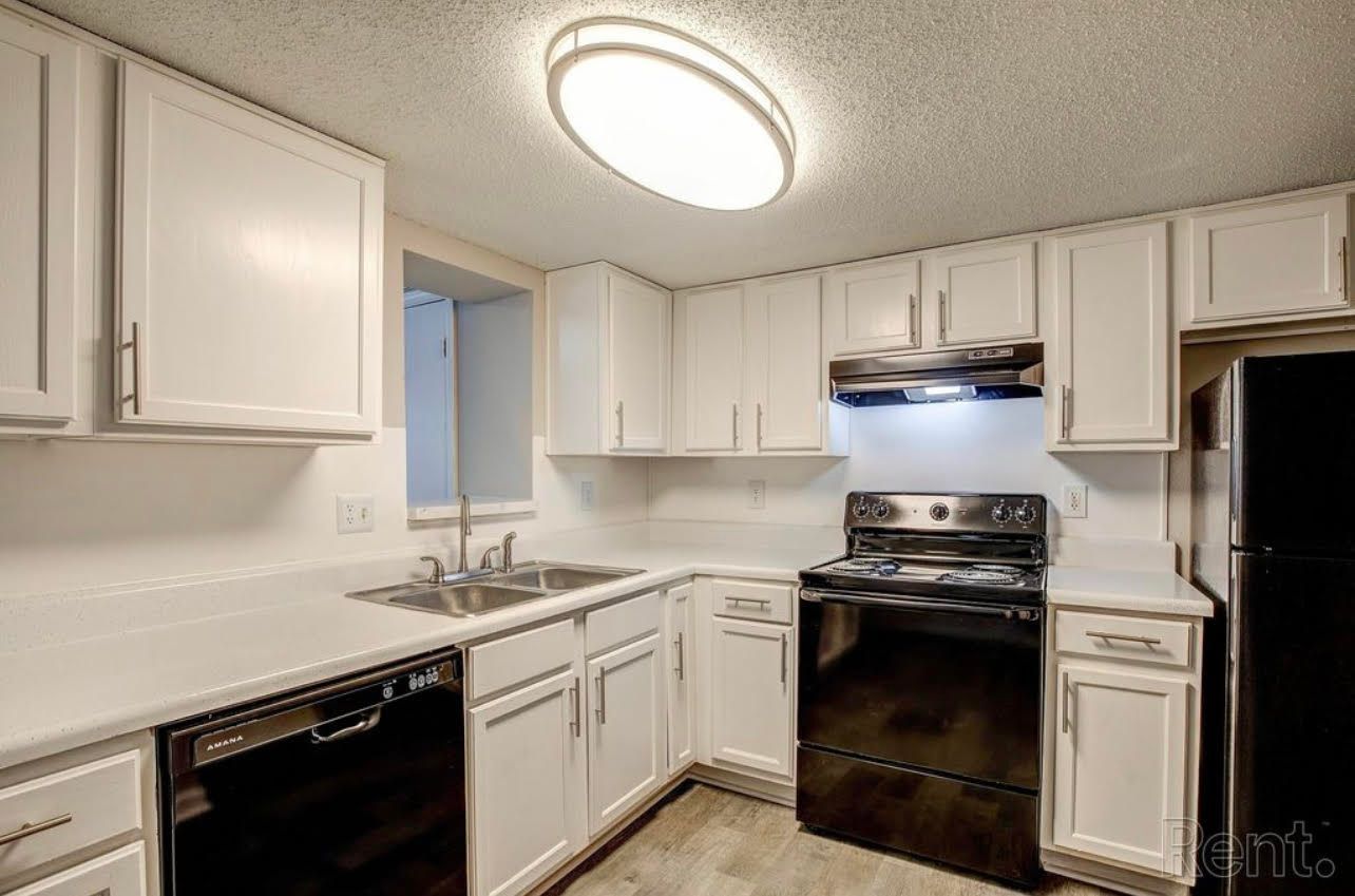 A kitchen with white cabinets and black appliances