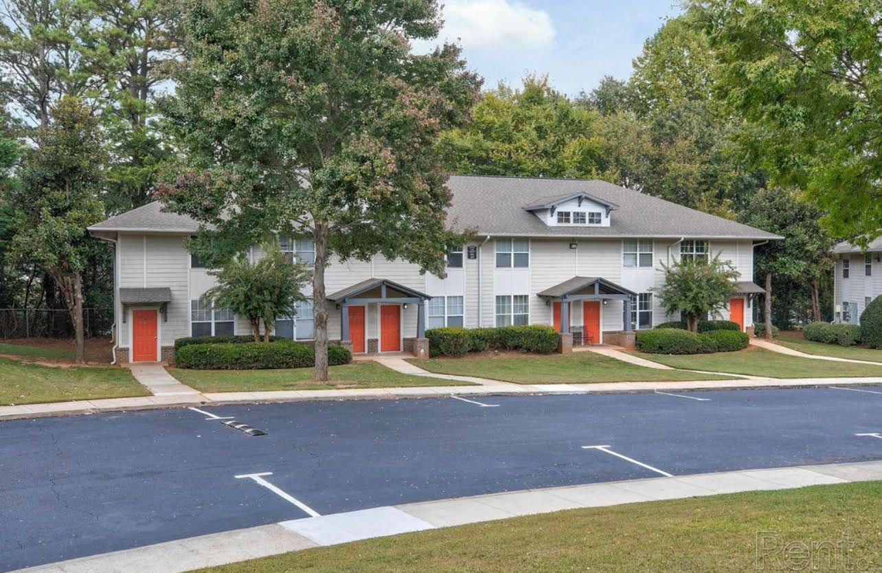 A row of apartment buildings with a parking lot in front of them.