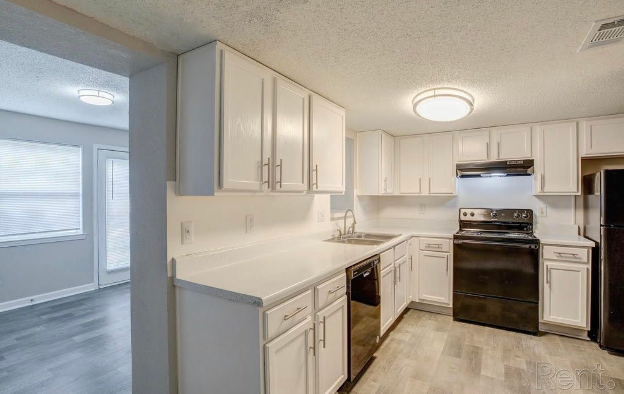 A kitchen with white cabinets , black appliances , a stove and a refrigerator.
