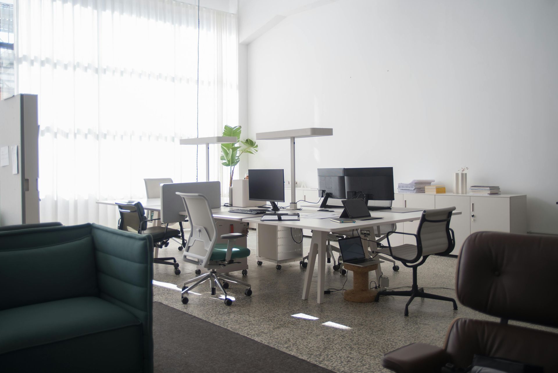 An office with a couch , chairs , desks and computers after cleaning for Clean Crew Milford.