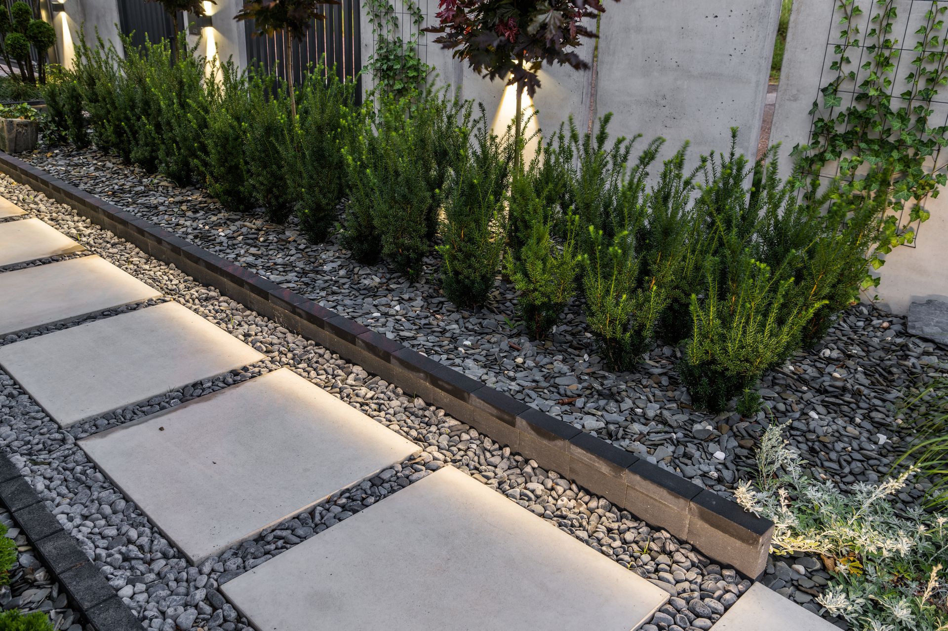 A walkway with gravel and plants on the side of it