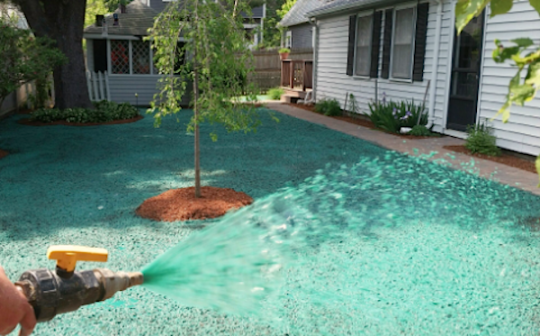 a person is watering a lawn with a hose in front of a house .