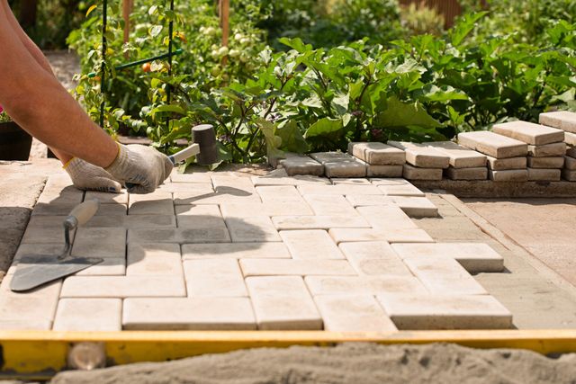 a man is laying bricks on a patio with a trowel .