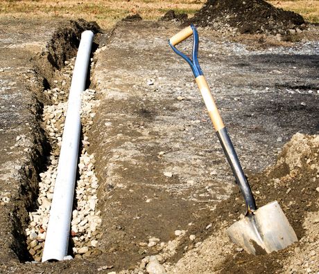 a shovel is sitting in the dirt next to a pipe .