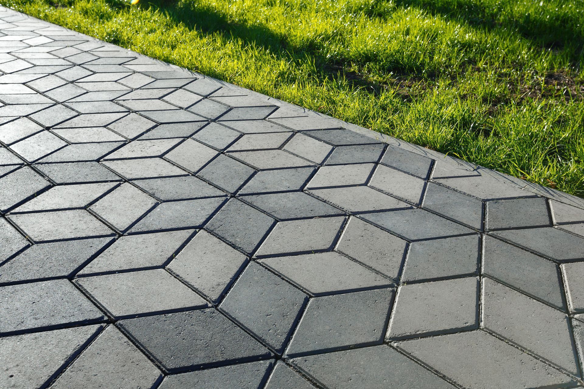 Gray and light gray geometric concrete pathway next to green grass.