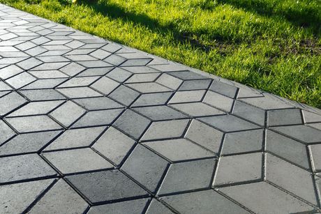 Gray and light gray geometric concrete pathway next to green grass.