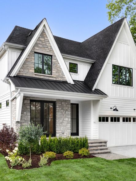 a white house with a black roof and a stone facade .