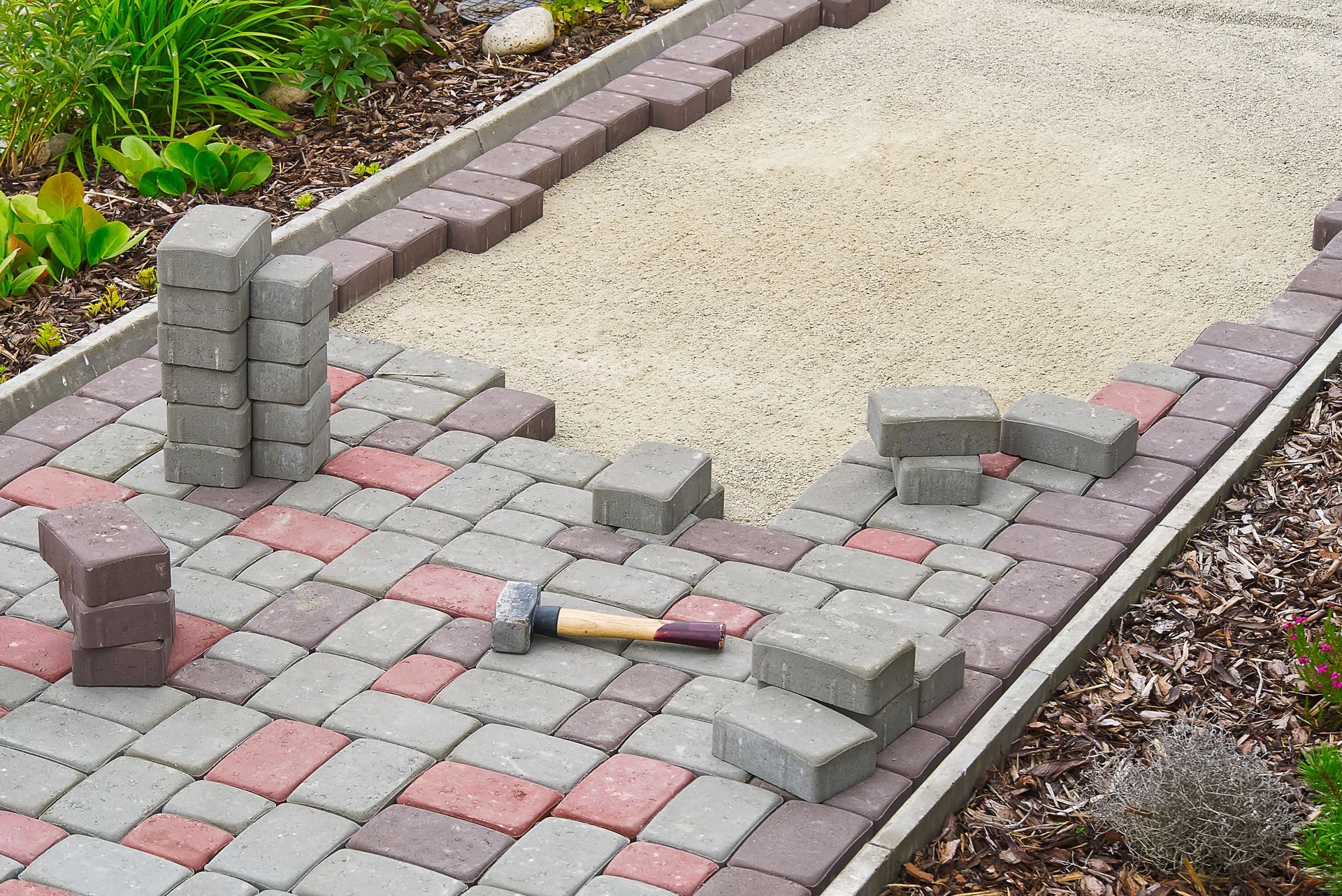 a hammer is laying on top of a brick walkway being built .