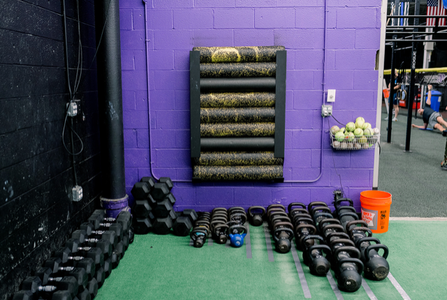 A gym with a lot of dumbbells and a purple wall.