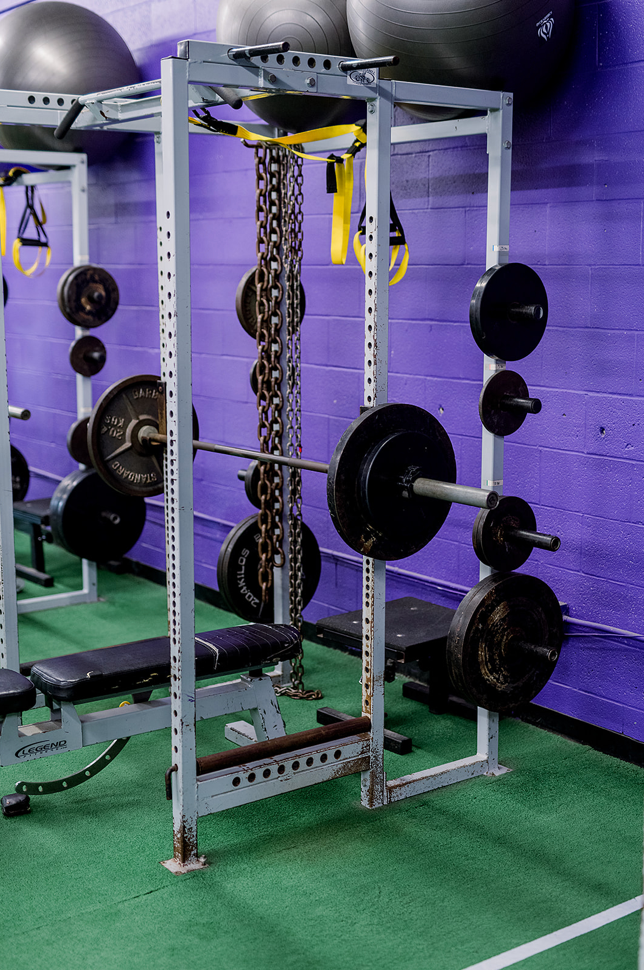 A gym with a lot of weights and a purple wall.