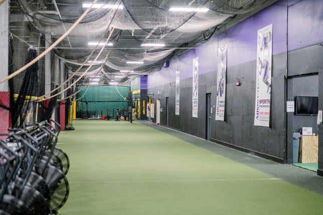 A long hallway in a gym with a lot of exercise equipment.