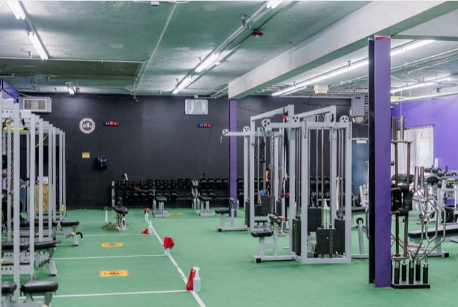 A gym filled with lots of exercise equipment and a green floor.
