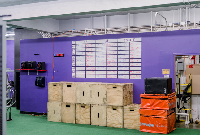 A gym with a purple wall and wooden boxes stacked on top of each other.