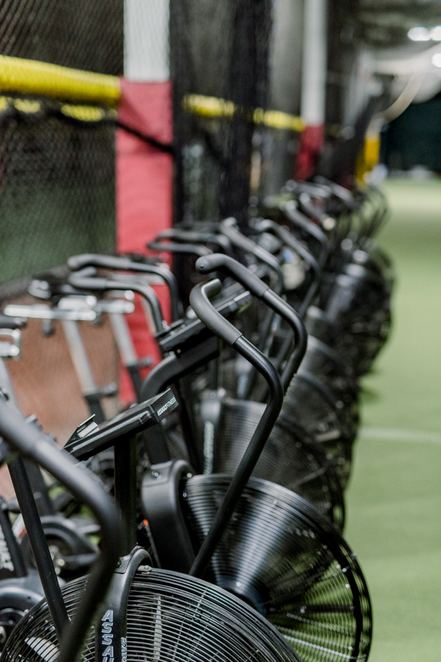 A row of exercise bikes are lined up in a gym.