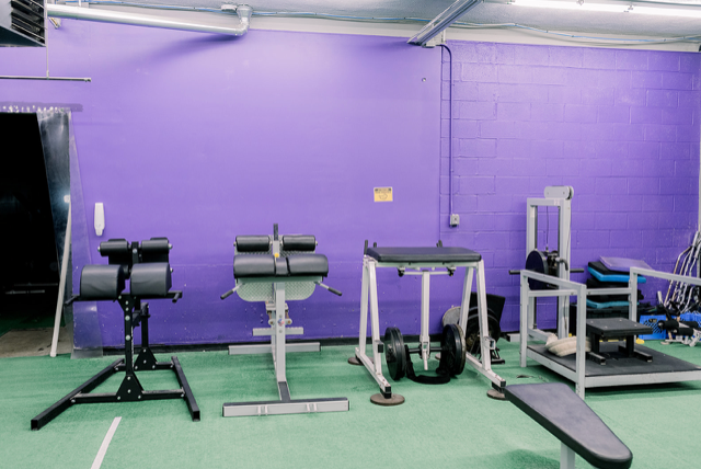 A gym with purple walls and lots of exercise equipment.