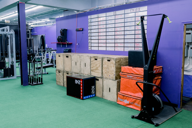 A gym with a purple wall and boxes on the floor