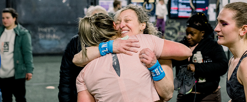 Athlete competing in CrossFit event while family and kids cheer from the sidelines