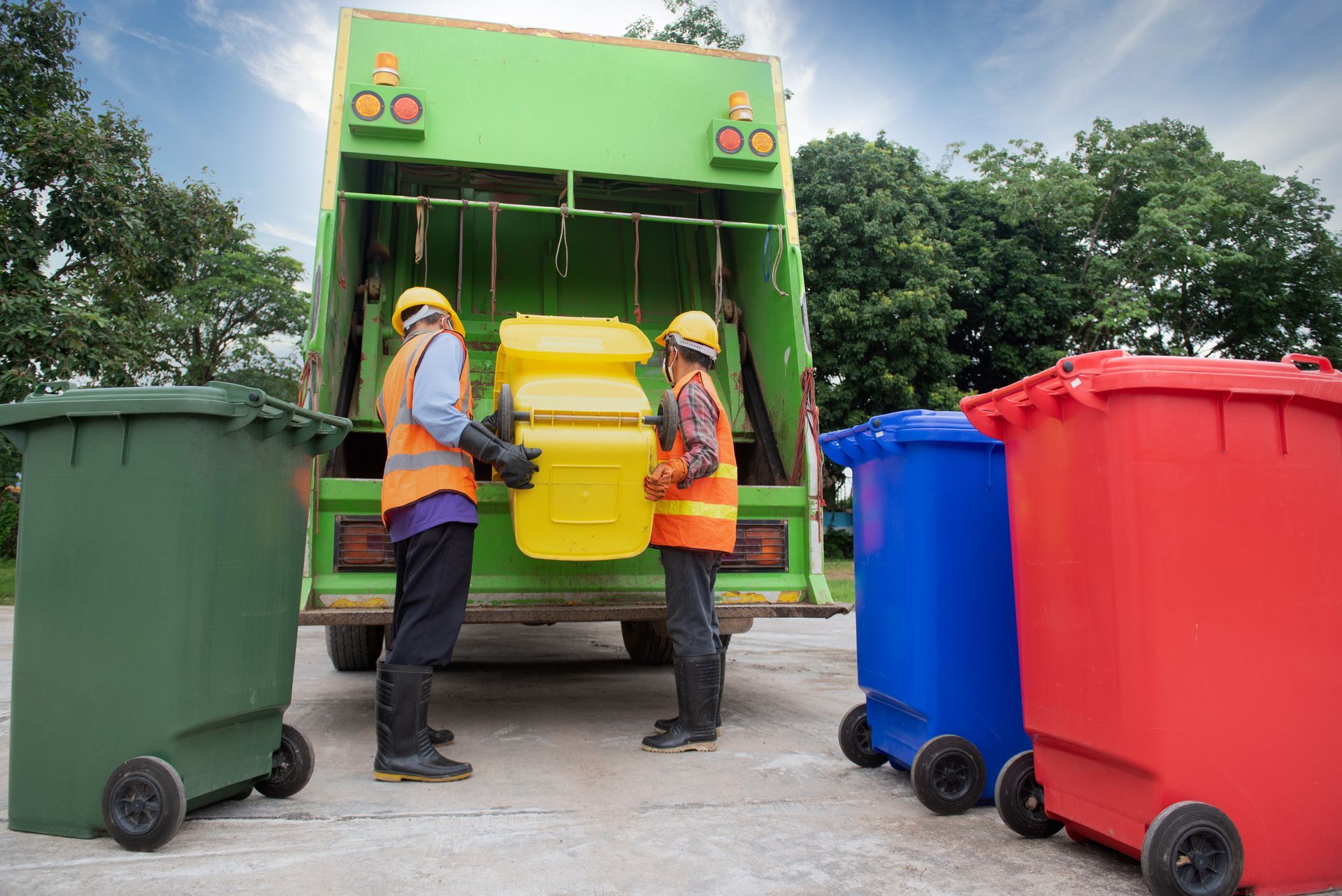 workers empty bins into a garbage truck during a trash removal service