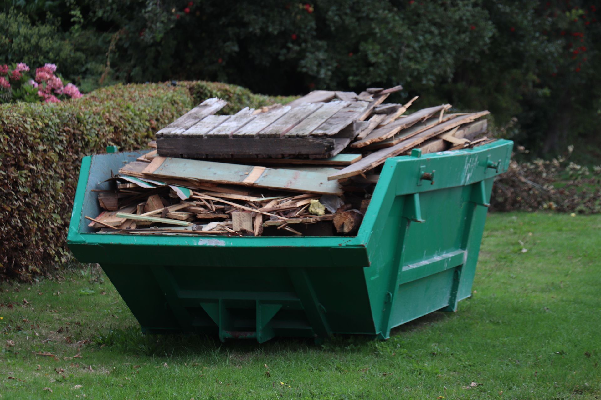 A large dumpster filled with mixed debris, wood, and plastic during a residential junk removal
