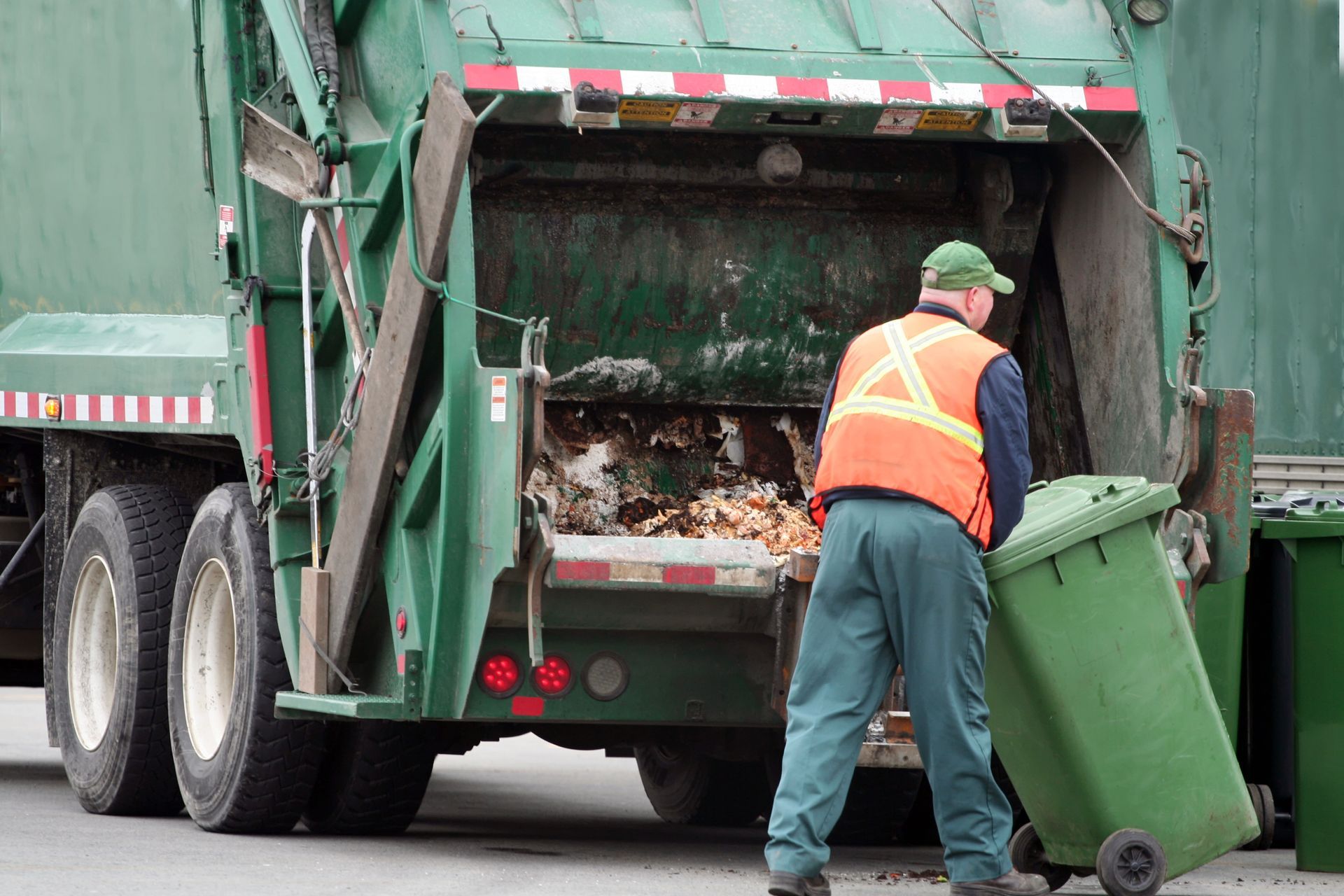 Tag-Man unloading debris from a roll-off container at a roofing project.
